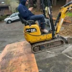 A man sits on a small excavator parked