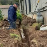 plumber working on in-ground pipe