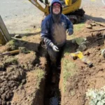 plumber working on underground pipe